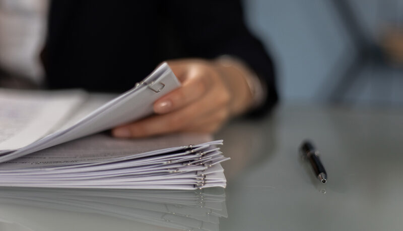 A person sifting through an organized stack of business documents.