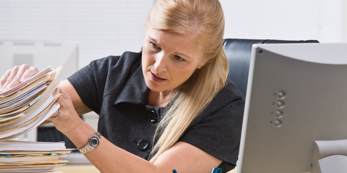 A woman going through a stack of paper documents.